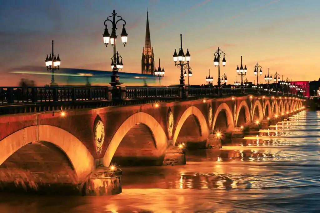 Vue nocturne sur la Garonne, le pont de pierre, qui est éclairé, et la basilique Saint-Michel à Bordeaux