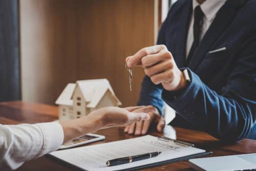 gros plan sur la main d'un agent immobilier qui tend les clefs d'un logement