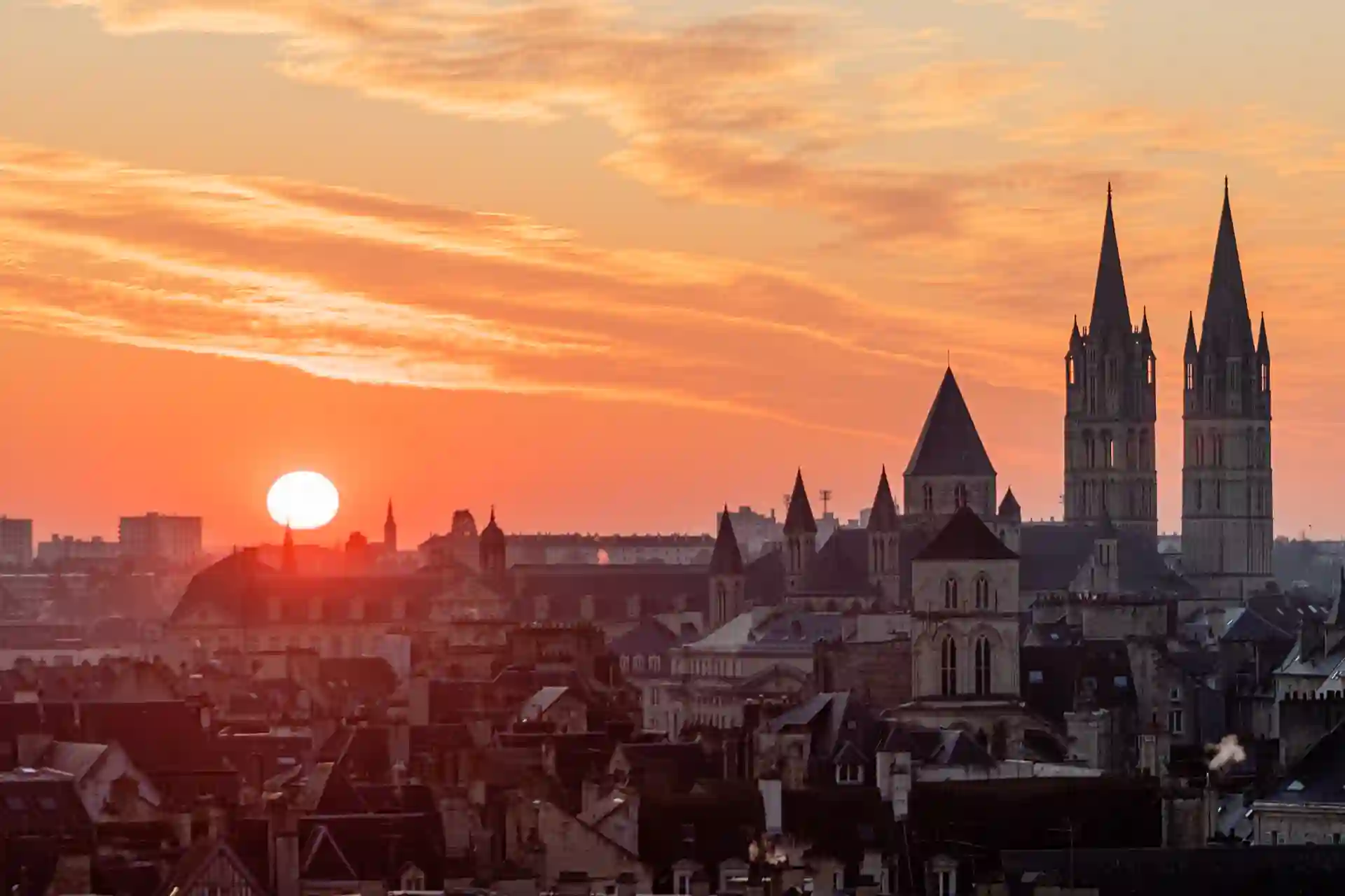 Investir dans un bien immobilier à Caen. L'image montre un coucher de soleil sur la ville caennaise.