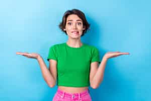 une femme sur un fond bleu uni mime l'équilibre d'une balance pour illustrer l'idée d'équilibre en remboursement de crédits et dépense de consommation