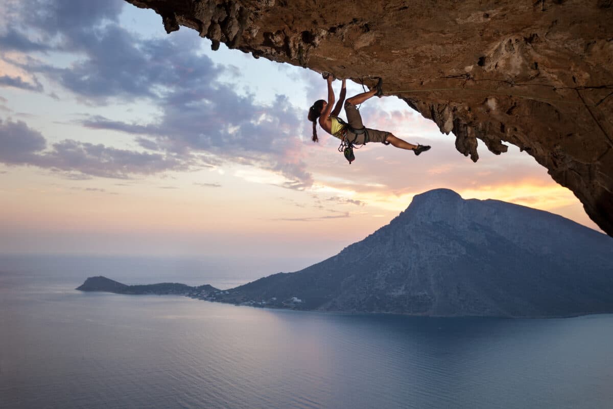 une jeune femme escalade une falaise au dessus de la mer cette image symbolise les risques de la vie à assurer