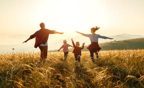 une famille heureuse court dans un champ de blé, l'image symbolise la liberté que poeut apporter un rachat de credit pour réaliser les projets d'une famille