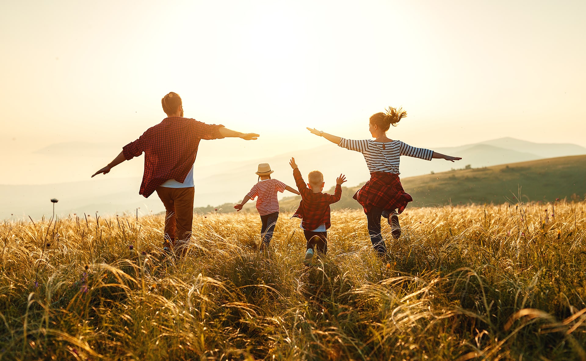 une famille heureuse court dans un champs de blé