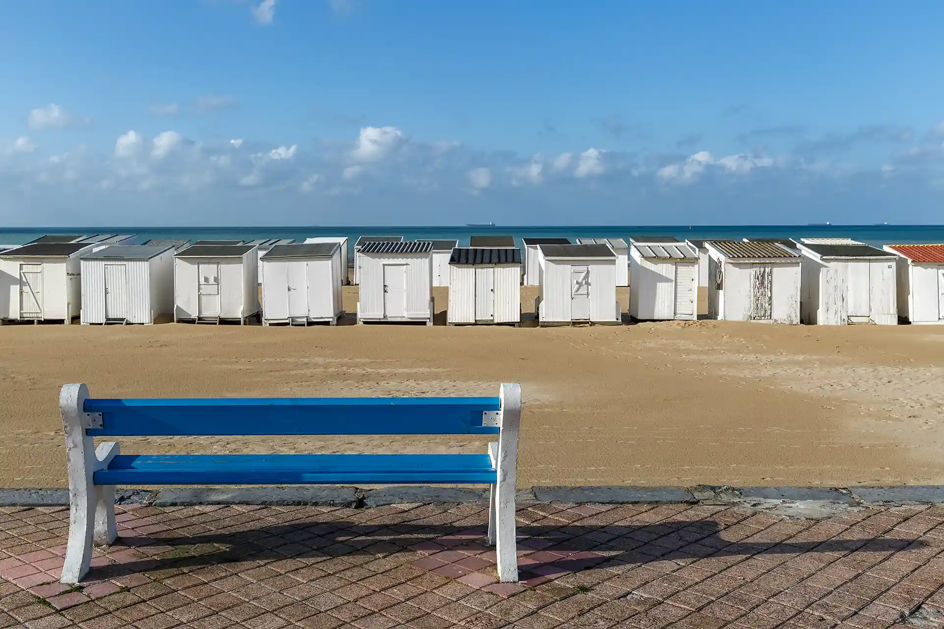 Regroupement de crédits dans la ville de Calais. L'image montre la plage de Calais avec ses célèbres cabanes et au premier plan un banc public bleu.