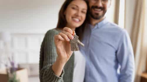 un jeune couple souriant se rejouit d'avoir bénéficié d'un rachat de crédit pour propriétaire