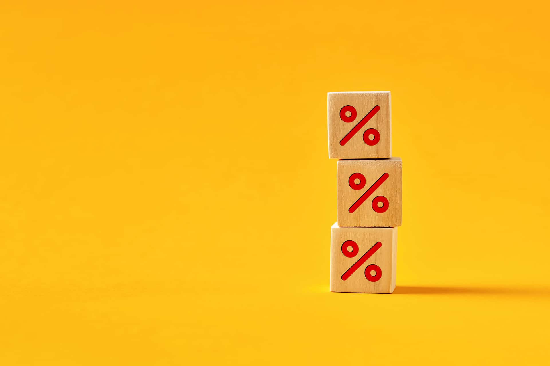 trois cubes en bois sur fond jaune avec le symbole % imprimé en rouge