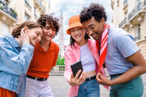 un groupe de touriste à Paris rigole en regardant une image sur un smartphone