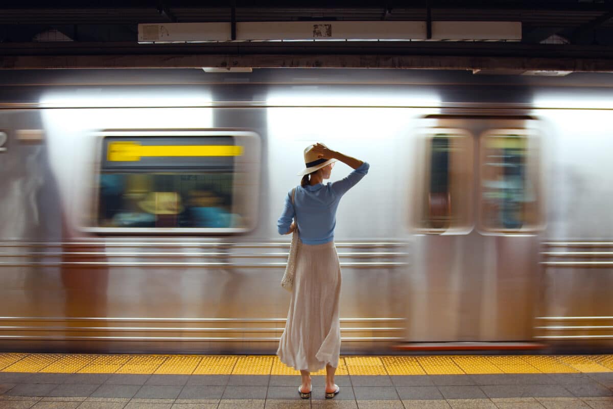 une femme regarde passer un train elle attend sur le quai l'arrivée du train qu'elle doit prendre, elle symbolise les délai de franchise de l'assurance emprunteur